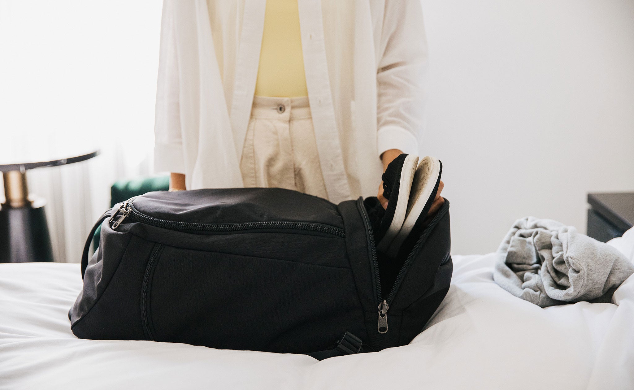 Person putting a pair of shoes in the end pocket of the Techonaut 30.